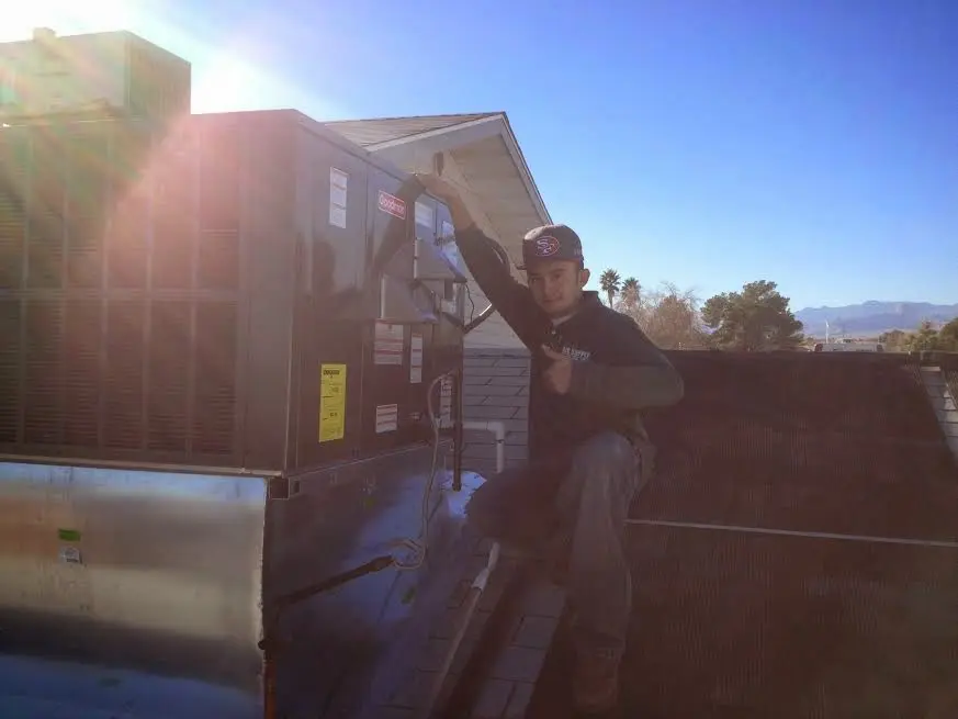 HVAC technician performing AC Tune-Up on a rooftop unit in Rockcreek