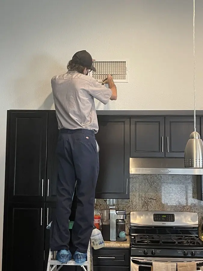 Technician inspecting an air vent during HVAC service in Rockcreek